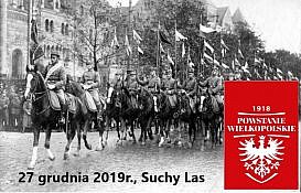 czarno-białe zdjęcie powstańców wielkopolskich na koniach, w dolnym prawym rogu czerwona flaga z białym orłem powstańczym i napisem 1918 Powstanie Wielkopolskie, na dole napis: 17 grudnia 2019 r. , Suchy Las